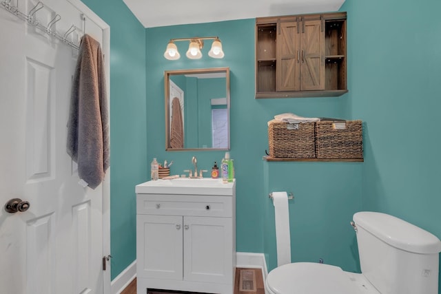 half bath with visible vents, vanity, toilet, and baseboards