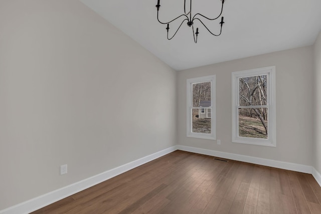 unfurnished dining area with a notable chandelier, dark wood finished floors, visible vents, and baseboards