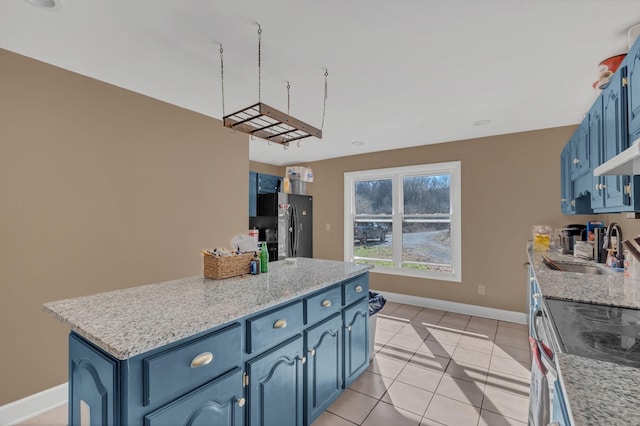 kitchen with baseboards, freestanding refrigerator, blue cabinets, a sink, and light tile patterned flooring