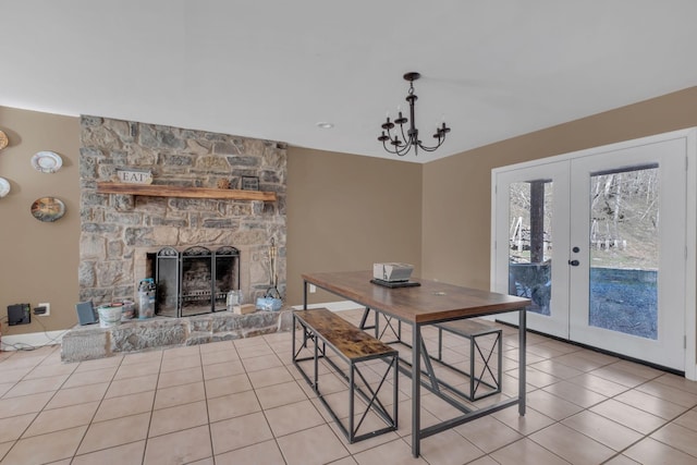 dining space featuring french doors, light tile patterned flooring, a fireplace, and a notable chandelier