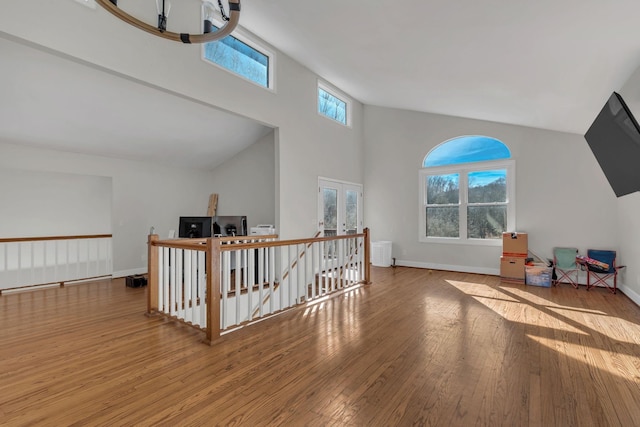 additional living space featuring high vaulted ceiling, french doors, baseboards, and hardwood / wood-style floors