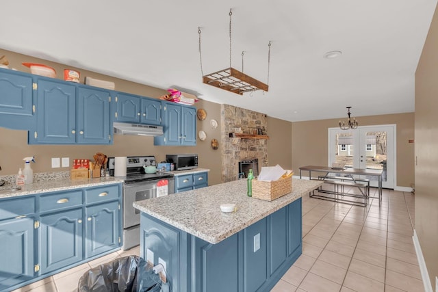 kitchen featuring blue cabinets, under cabinet range hood, light tile patterned floors, and stainless steel appliances