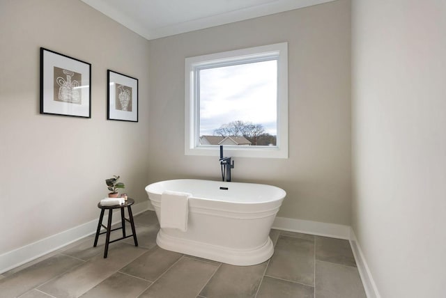 bathroom with a soaking tub, tile patterned floors, and baseboards