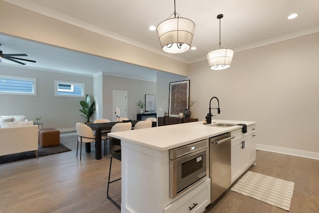 kitchen featuring dishwasher, open floor plan, a kitchen breakfast bar, light wood-type flooring, and white cabinetry