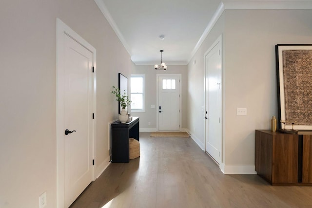 entryway featuring baseboards, light wood-style floors, a chandelier, and crown molding