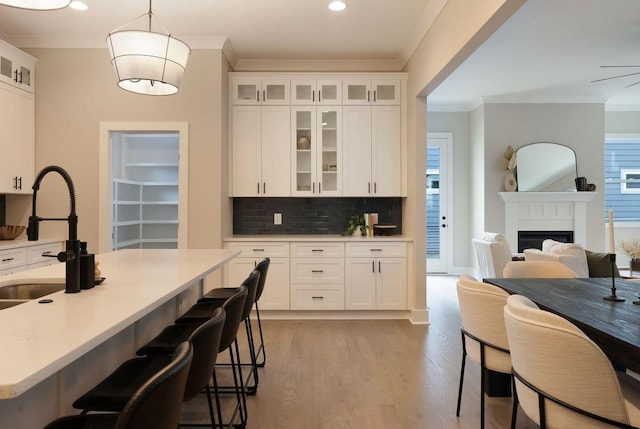 kitchen with a breakfast bar, a sink, white cabinets, and crown molding