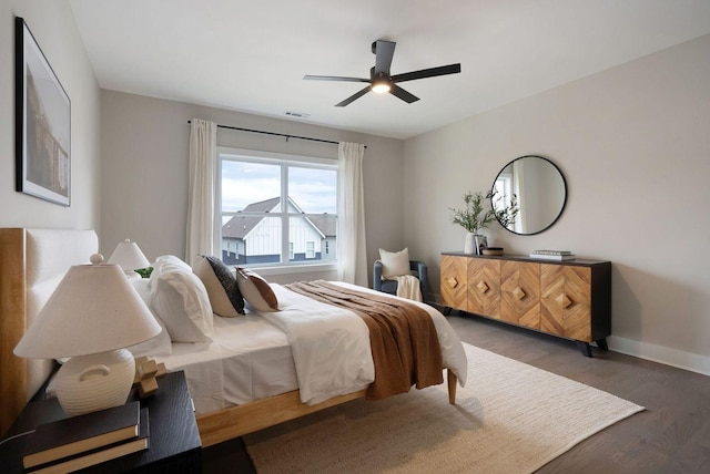 bedroom featuring a ceiling fan, wood finished floors, visible vents, and baseboards