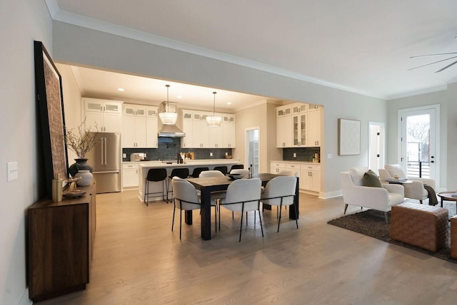 dining room featuring ornamental molding, ceiling fan, and light wood finished floors