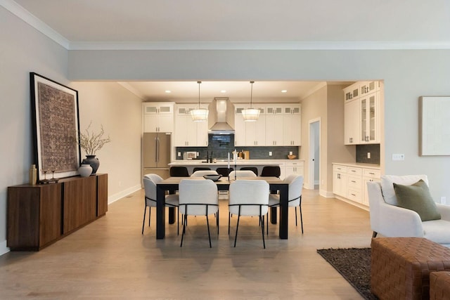 dining space with baseboards, light wood finished floors, recessed lighting, and crown molding