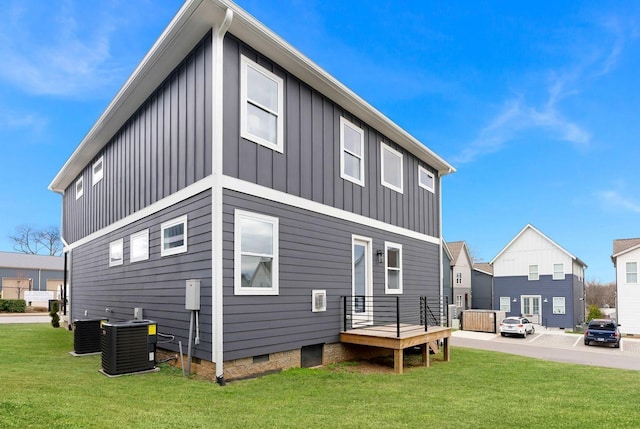 back of house featuring a yard, board and batten siding, and central air condition unit