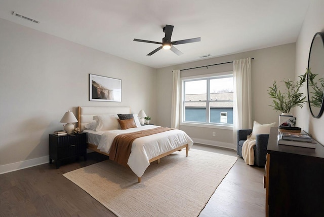 bedroom featuring baseboards, visible vents, ceiling fan, and wood finished floors