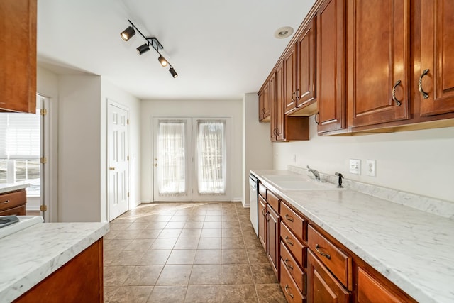 kitchen featuring light stone counters, brown cabinets, stainless steel dishwasher, a sink, and tile patterned flooring