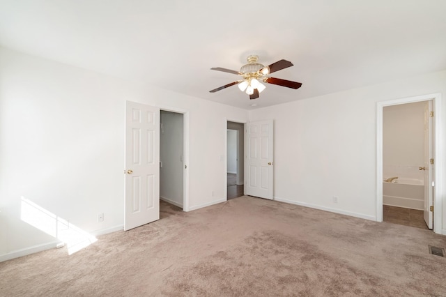 unfurnished bedroom featuring ensuite bathroom, carpet flooring, a ceiling fan, and baseboards