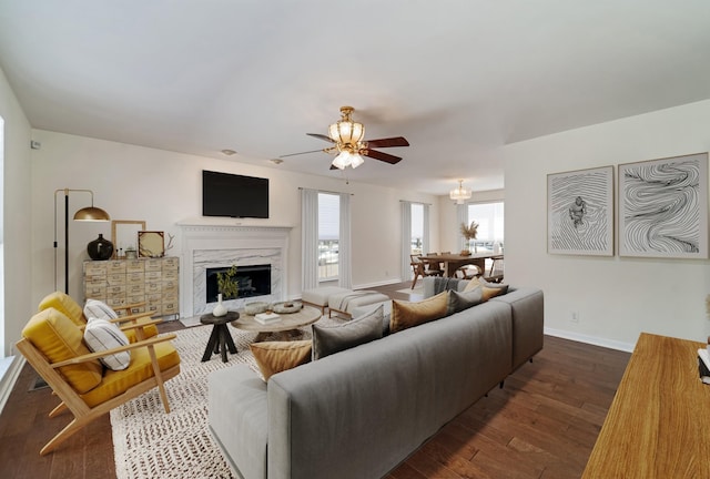 living area with a ceiling fan, dark wood-style flooring, baseboards, and a premium fireplace