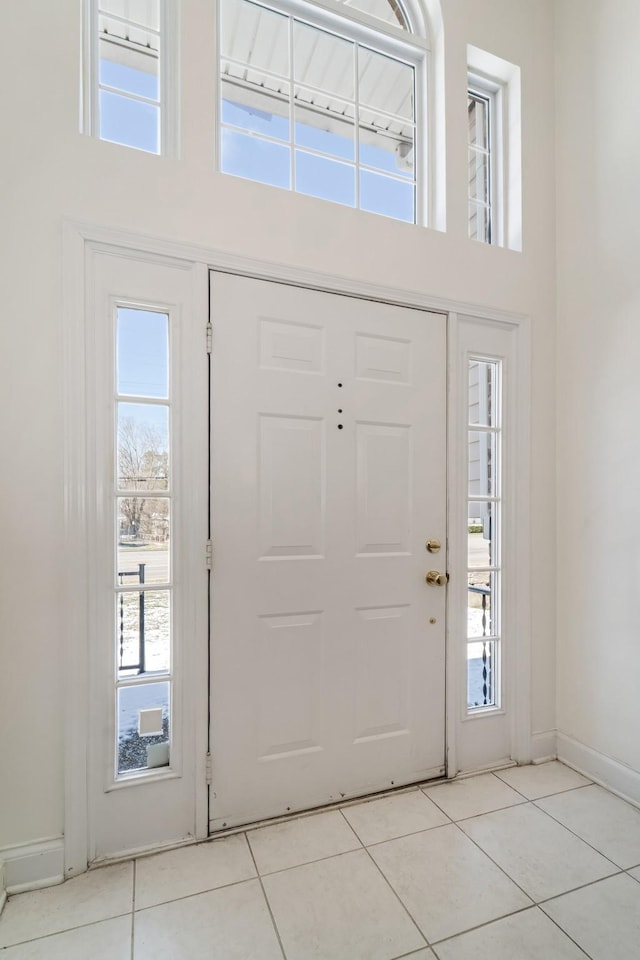 entryway with a towering ceiling, baseboards, and light tile patterned floors