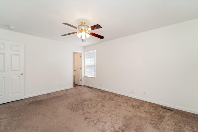 empty room featuring a ceiling fan, carpet, visible vents, and baseboards