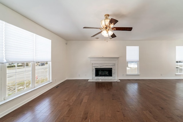 unfurnished living room featuring a ceiling fan, dark wood-style flooring, a fireplace, and baseboards