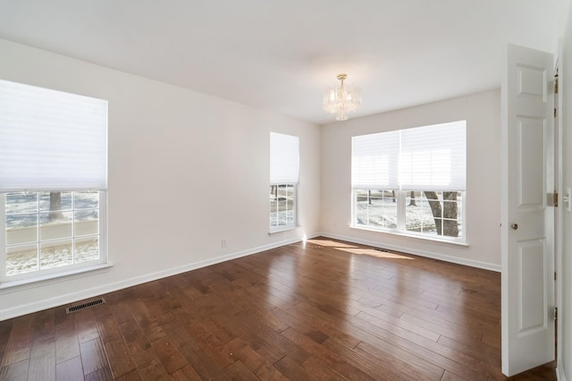 spare room featuring a chandelier, wood-type flooring, visible vents, and baseboards