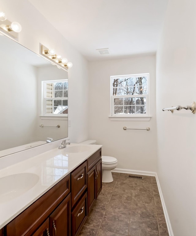 full bath with visible vents, a sink, toilet, and double vanity