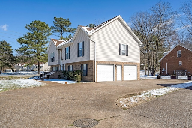 view of side of property featuring concrete driveway, brick siding, and an attached garage