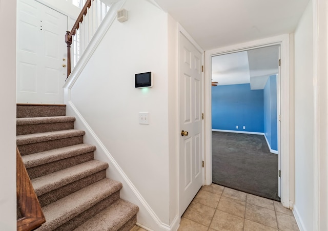 staircase featuring tile patterned flooring, baseboards, and carpet flooring