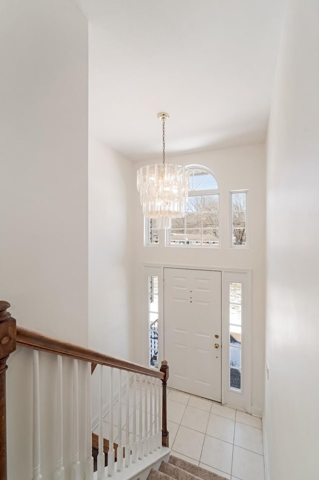 foyer entrance featuring stairway, a chandelier, light tile patterned flooring, and a towering ceiling