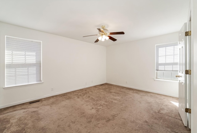 empty room featuring baseboards, carpet floors, visible vents, and a ceiling fan