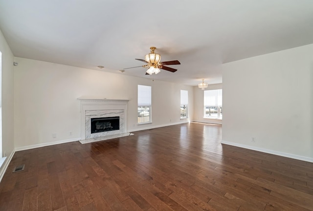 unfurnished living room featuring dark wood-style flooring, visible vents, baseboards, and a premium fireplace