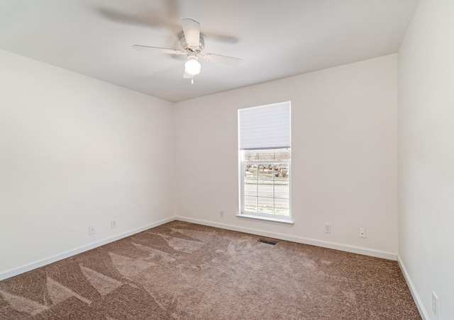 carpeted empty room featuring a ceiling fan, visible vents, and baseboards