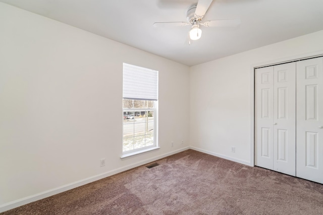 unfurnished bedroom featuring carpet floors, a closet, visible vents, ceiling fan, and baseboards