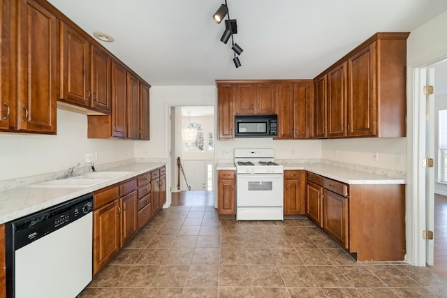 kitchen featuring brown cabinetry, white appliances, light countertops, and a sink