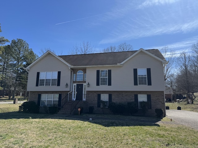 split foyer home with brick siding and a front lawn