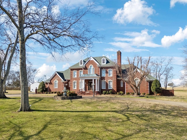 colonial house featuring a front yard, brick siding, and a chimney