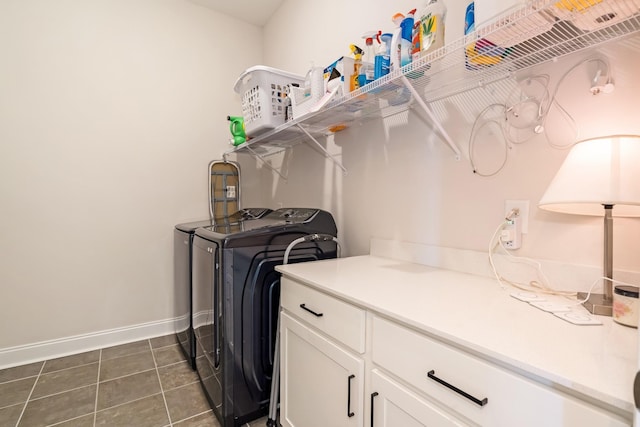 laundry room with dark tile patterned flooring, washer and clothes dryer, cabinet space, and baseboards