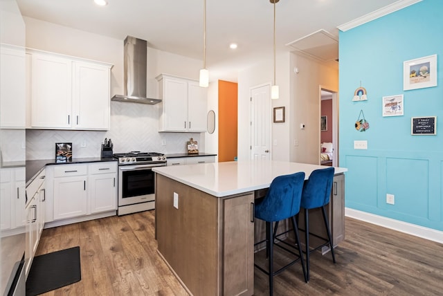 kitchen with a center island, dark wood-style flooring, decorative backsplash, gas stove, and wall chimney range hood