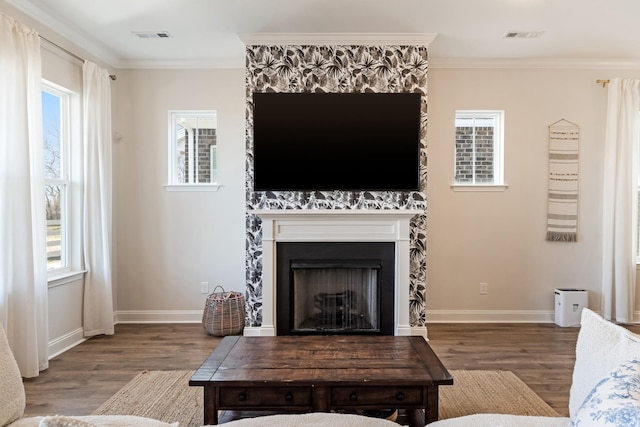 living room featuring a healthy amount of sunlight, a fireplace, and crown molding