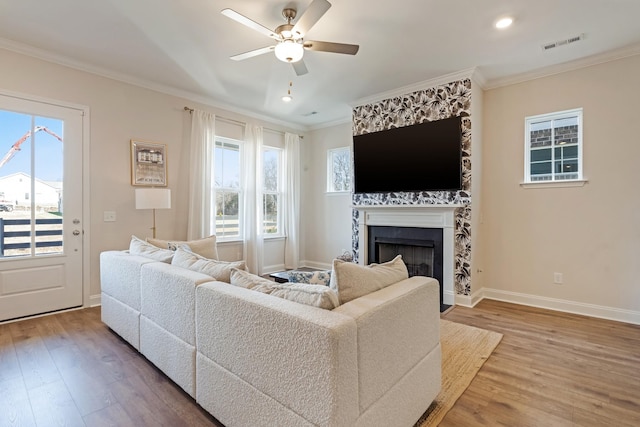 living area with visible vents, crown molding, and wood finished floors