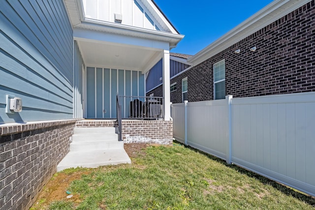 view of home's exterior with board and batten siding, a yard, brick siding, and fence