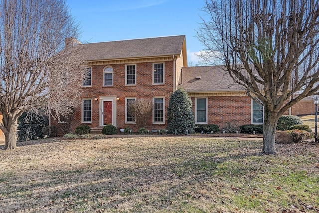 view of front of property featuring brick siding, roof with shingles, and a front yard