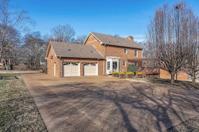 view of front of property with a garage, driveway, brick siding, and a chimney