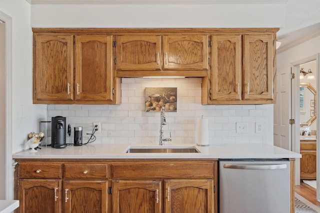 kitchen with dishwasher, light countertops, brown cabinetry, and a sink