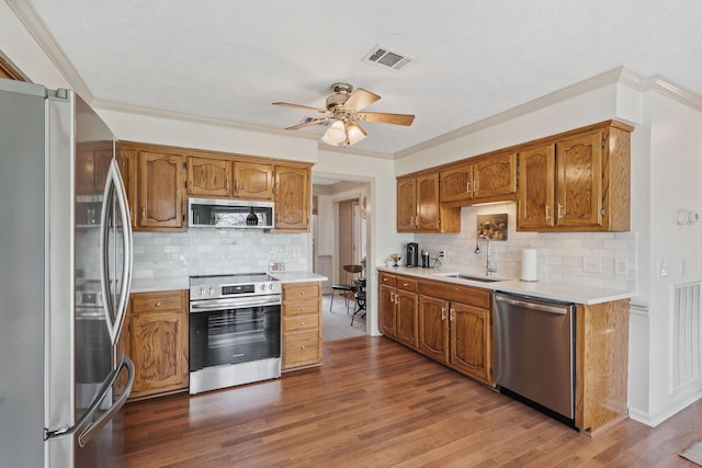 kitchen with visible vents, dark wood-style flooring, stainless steel appliances, light countertops, and a sink