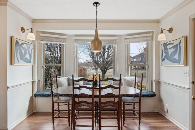 dining area featuring breakfast area, ornamental molding, baseboards, and wood finished floors