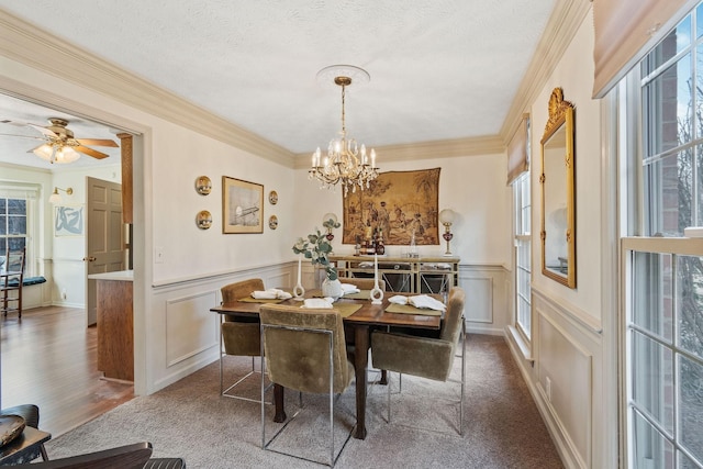 dining room with ornamental molding, a decorative wall, a textured ceiling, and ceiling fan with notable chandelier