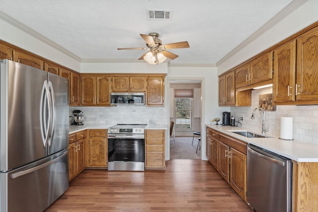 kitchen featuring appliances with stainless steel finishes, brown cabinets, visible vents, and a sink