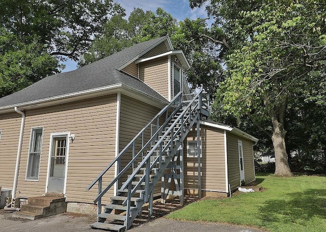 view of side of property with a yard and roof with shingles