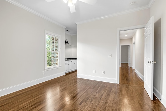 spare room with attic access, baseboards, ceiling fan, dark wood-style flooring, and crown molding