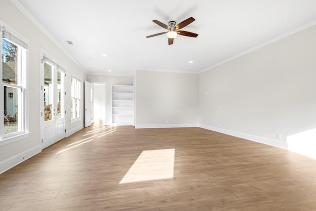 empty room featuring ornamental molding, wood finished floors, visible vents, and baseboards