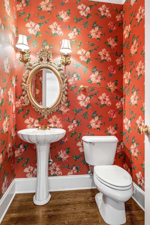 half bath featuring wood finished floors, toilet, and baseboards