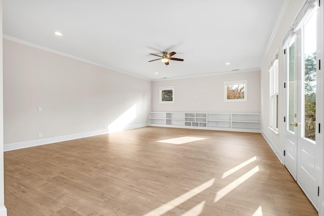 empty room featuring light wood finished floors, baseboards, and crown molding